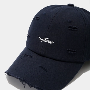 Close-up of distressed navy blue baseball cap featuring vintage embroidery and frayed details