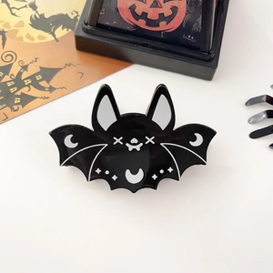 Détail d'une pince à cheveux noire en forme de chauve-souris avec lune et étoiles