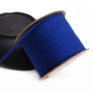 Macro view of blue 1.5mm non-elastic cotton cord on a wooden spool for DIY jewelry making
