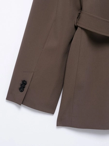 Detail of brown blazer sleeves with three black buttons and premium fabric texture