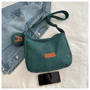 Detail of green corduroy tote bag with fashion leather patch and round coin purse charm