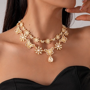 Detail of layered gold necklace with butterfly, flower motifs and large pear-shaped gem