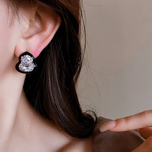 Detail of elegant black gourd stud earrings with sparkling crystals on a model's ear