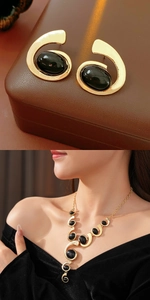 Detail of vintage gold swirl jewelry set with black oval stones on brown leather background