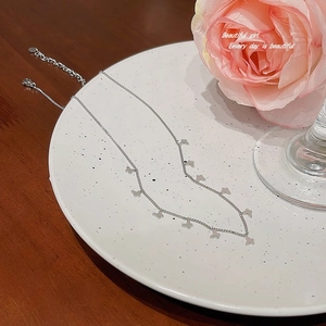Elegant silver stainless steel necklace with butterfly pendants on a ceramic plate