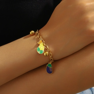 Gold stainless steel charm bracelet with enamel corn and eggplant pendants on wrist