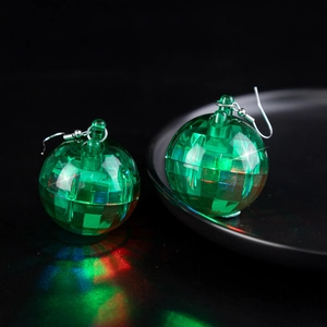 Macro shot of green faceted disco ball earrings with colorful light reflections on black