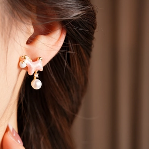 Detail of pink dog earring with pearl and crystal drop on female model ear