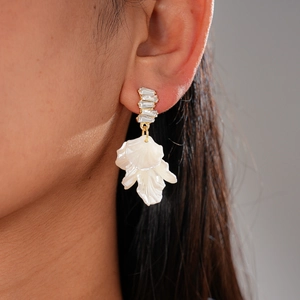 Detail of elegant gold drop earrings featuring white petals and sparkling zircon crystals