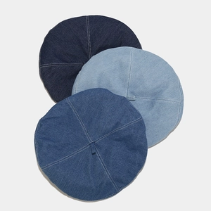 Flat lay of denim beret hats in dark, medium and light blue washes with stitching detail