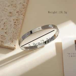 Detail view of silver stainless steel bangle with star engraving and cubic zirconia stones