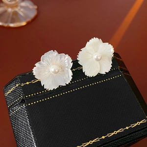 Gros plan de boucles d'oreilles fleurs en nacre avec perles sur une boîte à bijoux