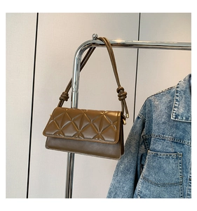 Close-up of brown quilted crossbody bag with geometric triangle patterns and knotted strap