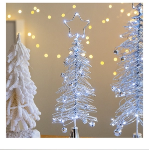 Close-up of silver Christmas tree ornament with LED lights and bells in festive bokeh