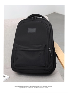 Close-up of durable black nylon backpack with metal zippers on a gray fabric sofa
