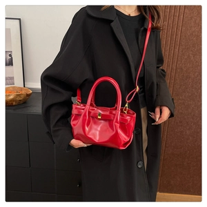 Detail of red glossy leather handbag with bow decoration and gold metal hardware