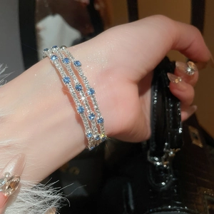 Close-up of triple-layer bracelet with blue and white zircons on a model wrist