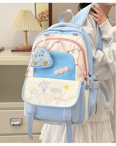 Detail of color-block school backpack with cartoon embroidery and pink zippers