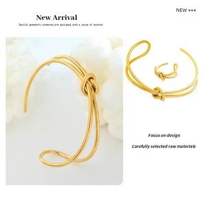 Close-up of golden knotted double-line bangle and matching minimalist twist ring set