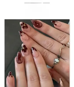Detail of short almond press-on nails with cherry red, pink floral art and gold beads