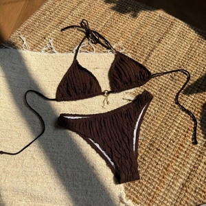 Detail of crinkle fabric bikini top with gold ring and pearl starfish charms