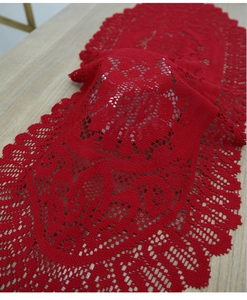 Close-up of red lace table runner with intricate crochet patterns on wooden table