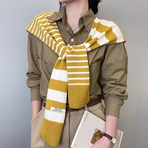 Detail of yellow and white striped knitted shawl draped over shoulders for a stylish look