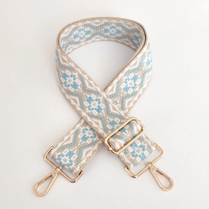 Close-up of ethnic geometric jacquard bag strap with polished gold metal swivel hooks