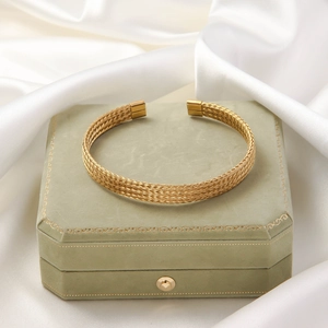 Detailed view of golden twisted braided cuff bracelet on green velvet jewelry box