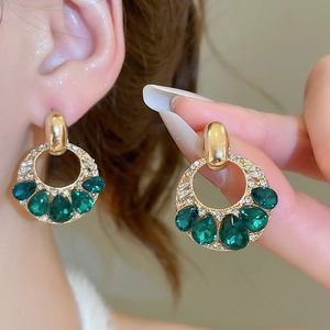 Dettaglio degli orecchini vintage con pietre a goccia color smeraldo e diamanti bianchi