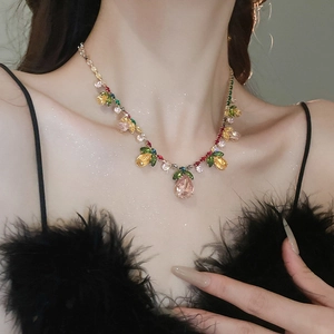 Close-up of elegant zircon flower and fruit pendant necklace on model with black feathers