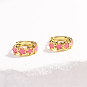 Detailed view of gold hoop earrings with pink enamel stars on white marble