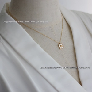 Detail of a 18K gold plated square necklace featuring a bee on white shell pendant