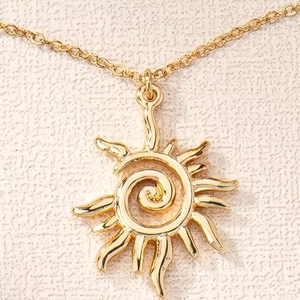 Macro shot of gold sun pendant featuring a spiral center and radiant hollowed-out rays