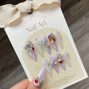Eleganti unghie press-on stiletto viola fatte a mano con strass e cristalli di lusso.