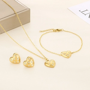 Detail of gold heart jewelry set with necklace bracelet and stud earrings with zircons