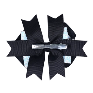 Detail showing the silver metal alligator clip and black ribbed ribbon texture of the hair bow