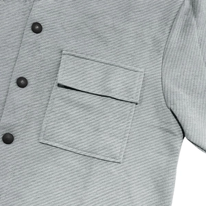Macro detail of a grey corduroy shirt showing buttoned chest pocket and fine ribbed fabric