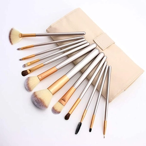 Detailed set of 12 professional makeup brushes with silver handles and a beige storage bag