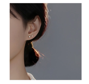Close-up of minimalist S999 silver heart stud earrings with iridescent cubic zirconia