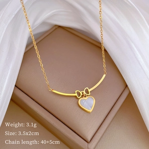 Detail of gold bow necklace with heart pendant, size 3.5x2cm on luxury silk background