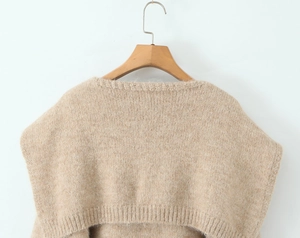 Detail of camel beige knit sweater featuring chunky texture and ribbed hem on hanger