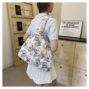 Lace butterfly canvas tote bag shown worn over the shoulder in a minimalist indoor setting
