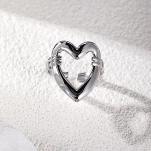 Detailed close-up of hollow heart silver ring with open design on textured surface