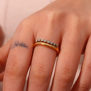 Makroaufnahme eines minimalistischen Goldrings mit kleinen Türkissteinen an der Hand