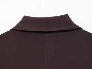 Détail du col d'une veste marron chocolat montrant la précision des coutures tissées