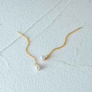 Detail of S925 silver tassel earrings with white pearls and sparkling zircons on white surface