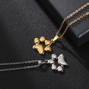 Detail of gold and silver cat paw pendants on stainless steel chains over black leather