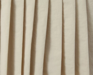 Nahaufnahme der beigen Faltenstoffstruktur und des weichen, gerafften Materialdesigns