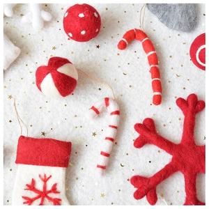 Collection of festive red and white wool felt Christmas ornaments on starry plush background